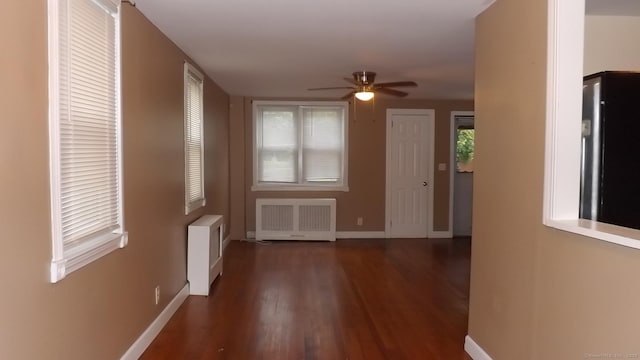interior space with radiator heating unit, a ceiling fan, baseboards, and wood finished floors
