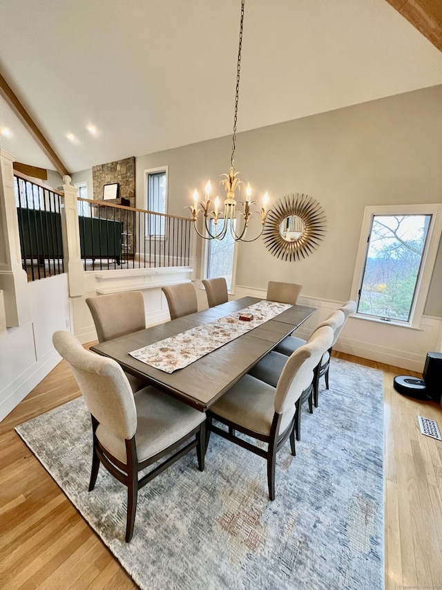 dining area with light wood-style flooring, beam ceiling, baseboards, visible vents, and an inviting chandelier