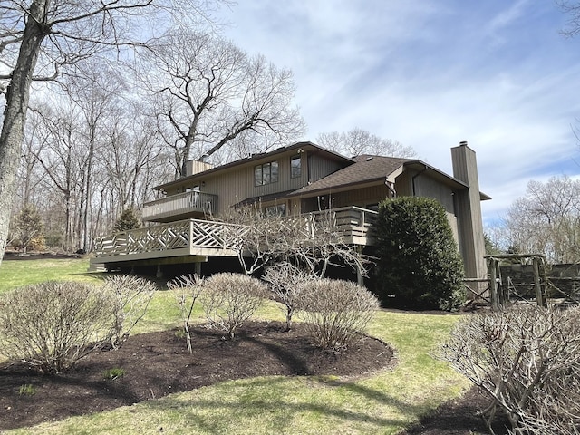 view of property exterior featuring a chimney, a yard, and a deck