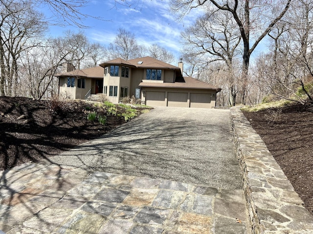 view of front of home featuring a chimney, an attached garage, and driveway