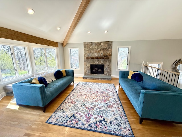 living area featuring light wood-type flooring, a healthy amount of sunlight, baseboards, and lofted ceiling with beams