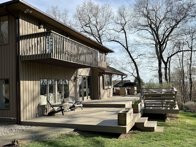 rear view of house featuring a wooden deck and a balcony