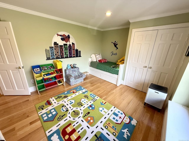 bedroom with wood finished floors, a closet, baseboards, and ornamental molding