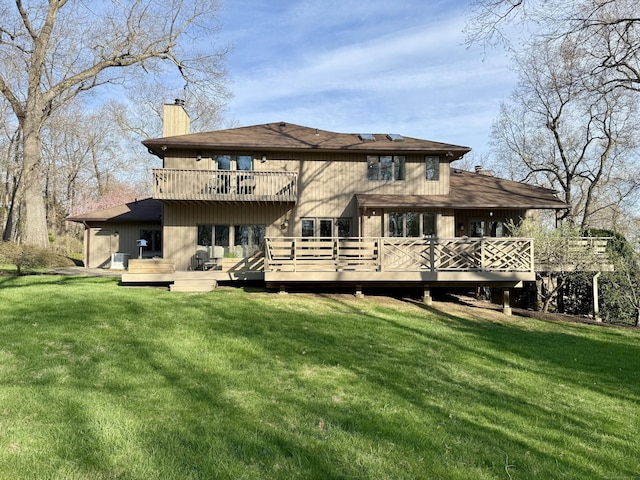 rear view of property featuring a wooden deck, a lawn, a chimney, and a balcony