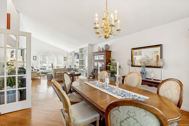 dining room with light wood-style floors, an inviting chandelier, and lofted ceiling