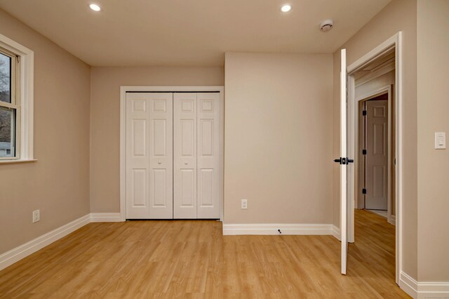 unfurnished bedroom with light wood finished floors, recessed lighting, baseboards, and a closet