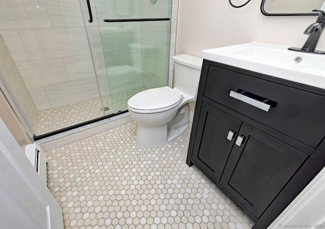 bathroom with a stall shower, toilet, and vanity