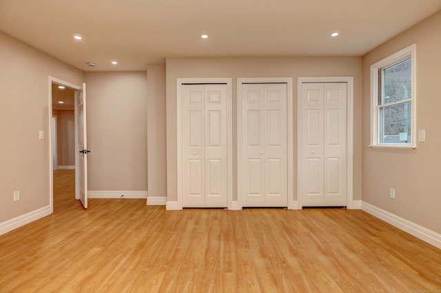 unfurnished bedroom with two closets, light wood-type flooring, baseboards, and recessed lighting