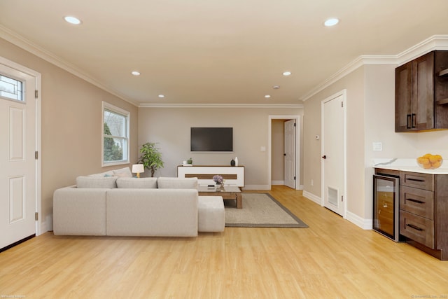 living area with light wood-style flooring, recessed lighting, beverage cooler, baseboards, and ornamental molding