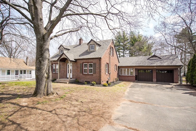 view of front of property with a shingled roof, aphalt driveway, a garage, brick siding, and a chimney
