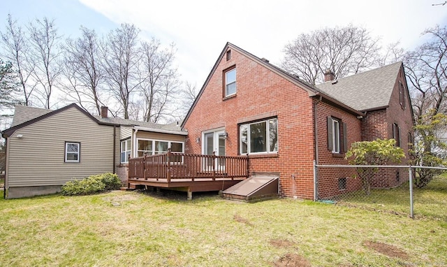 rear view of house featuring brick siding, a chimney, a yard, and a deck