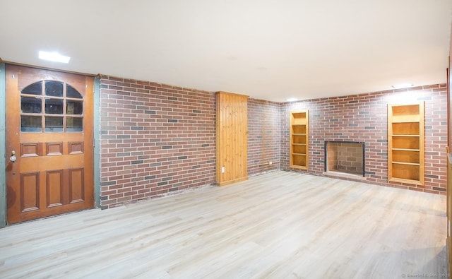 unfurnished living room featuring light wood-type flooring, built in shelves, and a fireplace