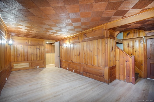 bonus room featuring wood finished floors, wooden walls, and stairway