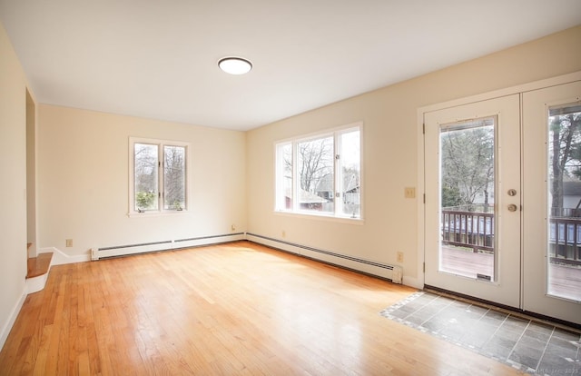 spare room with a baseboard heating unit, hardwood / wood-style flooring, and a wealth of natural light