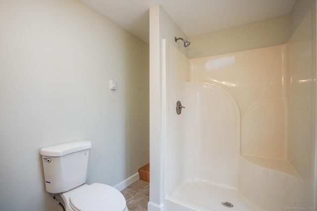 bathroom featuring tile patterned flooring, baseboards, a shower, and toilet