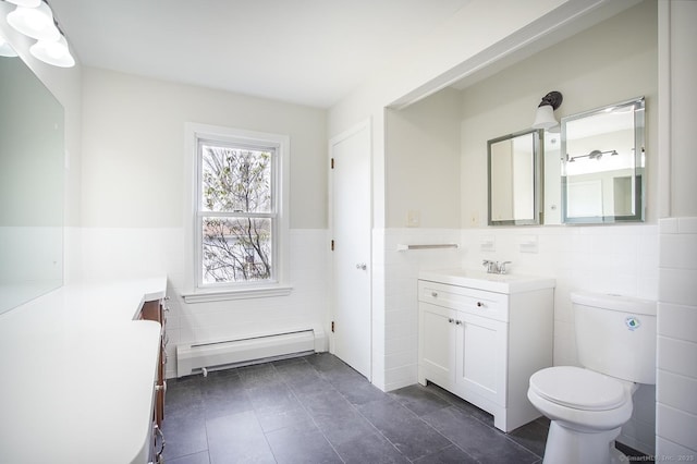 bathroom with tile walls, vanity, a wainscoted wall, a baseboard heating unit, and toilet