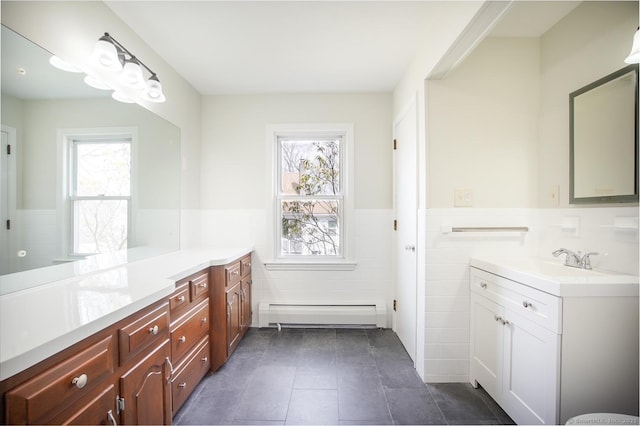 bathroom with tile patterned flooring, vanity, a wainscoted wall, tile walls, and a baseboard heating unit