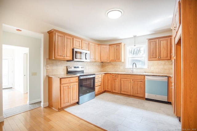 kitchen with light stone counters, a sink, appliances with stainless steel finishes, and tasteful backsplash
