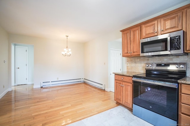 kitchen featuring light stone countertops, brown cabinets, appliances with stainless steel finishes, backsplash, and a notable chandelier