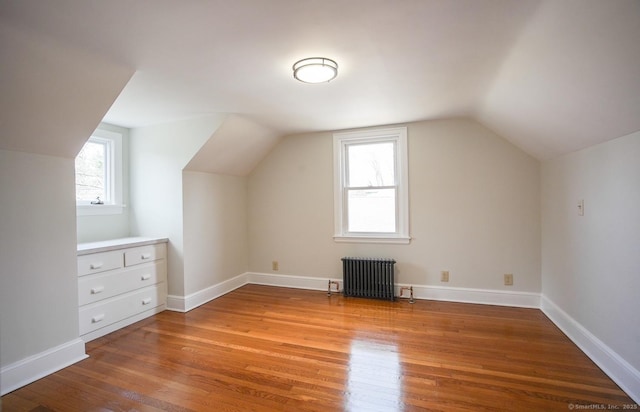 additional living space with radiator heating unit, baseboards, wood finished floors, and lofted ceiling