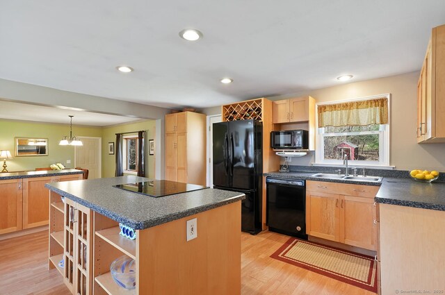 kitchen featuring light brown cabinets, a sink, dark countertops, black appliances, and a kitchen island