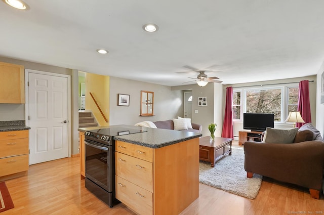 kitchen featuring open floor plan, a center island, stainless steel electric range, and light wood-style flooring