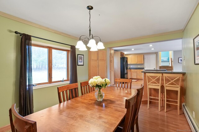 dining room featuring an inviting chandelier, light wood-type flooring, crown molding, recessed lighting, and a baseboard heating unit