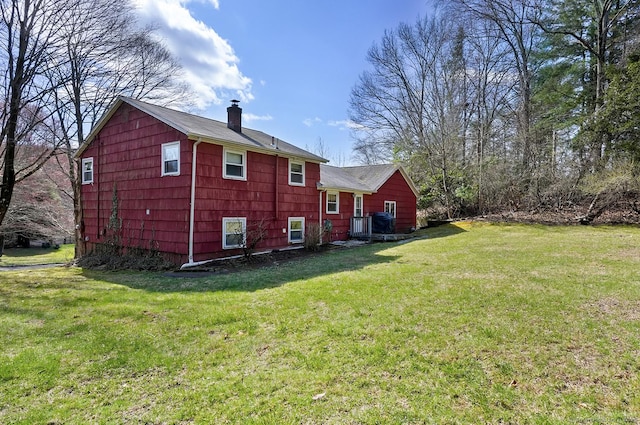 back of house with a yard and a chimney
