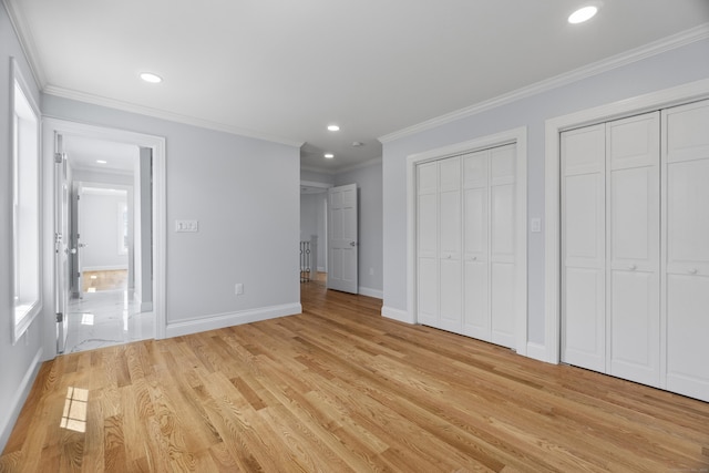 unfurnished bedroom featuring two closets, light wood-style floors, baseboards, and recessed lighting