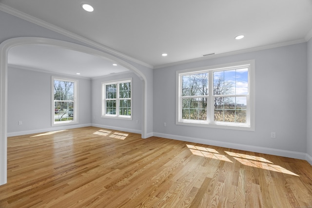 unfurnished living room with recessed lighting, arched walkways, baseboards, and ornamental molding