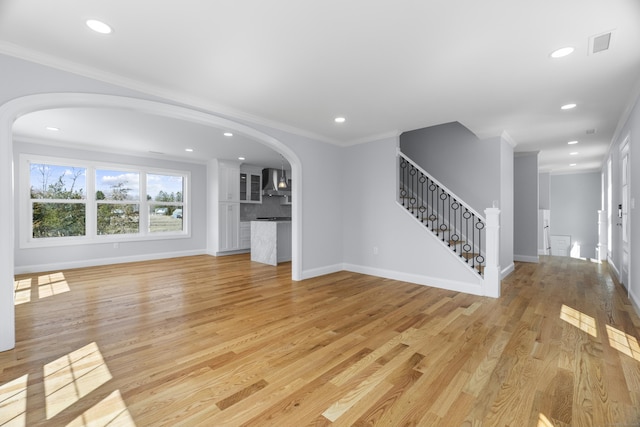 unfurnished living room featuring visible vents, arched walkways, crown molding, recessed lighting, and light wood-style flooring