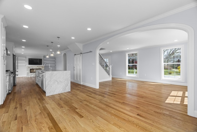 interior space featuring arched walkways, ornamental molding, recessed lighting, stairway, and light wood-style flooring
