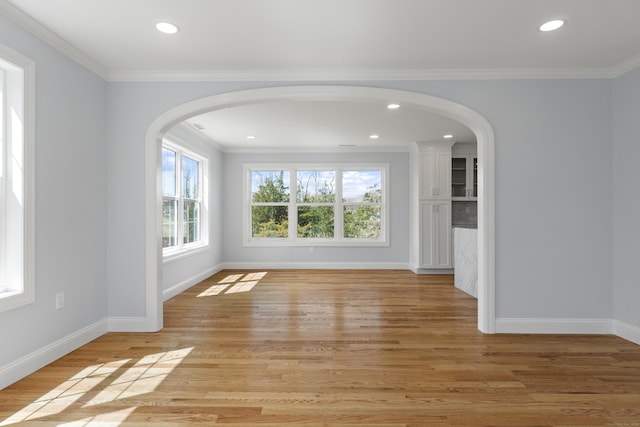 spare room featuring arched walkways, recessed lighting, baseboards, and light wood-type flooring