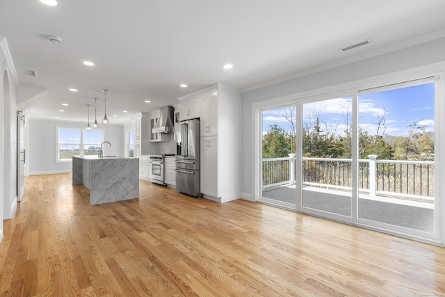 kitchen featuring baseboards, wall chimney range hood, crown molding, visible vents, and premium appliances