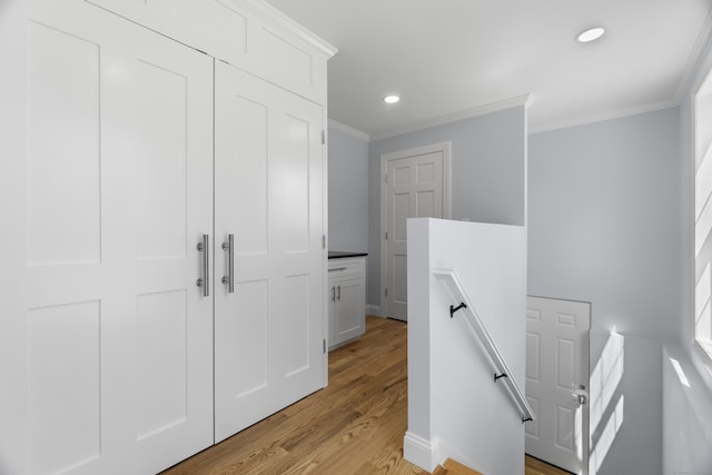 hallway with light wood-type flooring, recessed lighting, an upstairs landing, and crown molding