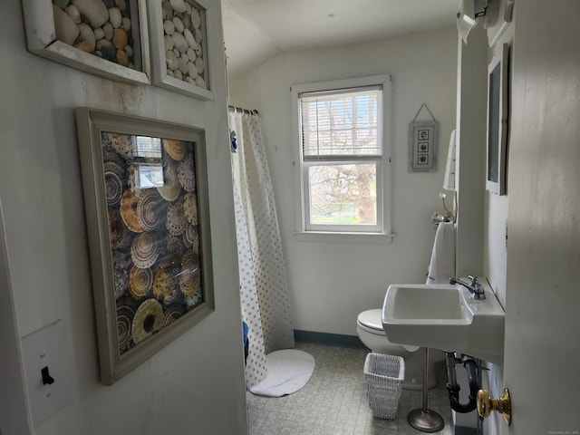 bathroom featuring baseboards, a shower with shower curtain, a sink, toilet, and vaulted ceiling