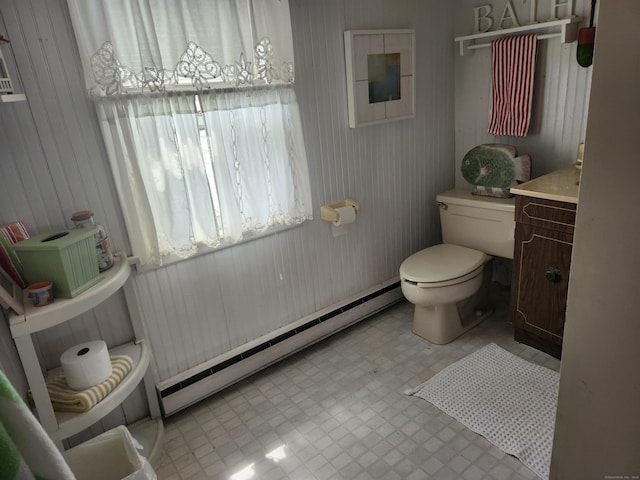 half bathroom with toilet, tile patterned floors, vanity, and baseboard heating