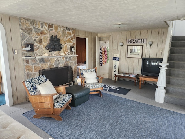 living room with wood walls, stairway, and carpet floors