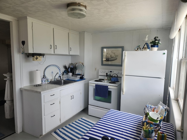 kitchen with concrete floors, white appliances, light countertops, white cabinets, and a sink