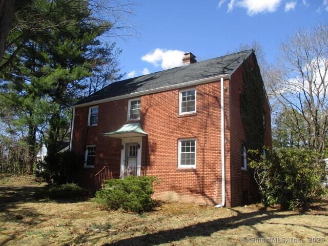 view of front of house featuring brick siding and a chimney