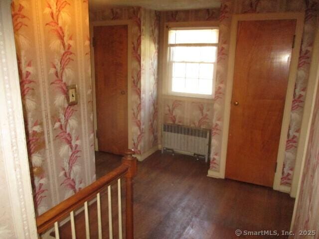 interior space featuring radiator heating unit, baseboards, wood finished floors, and wallpapered walls