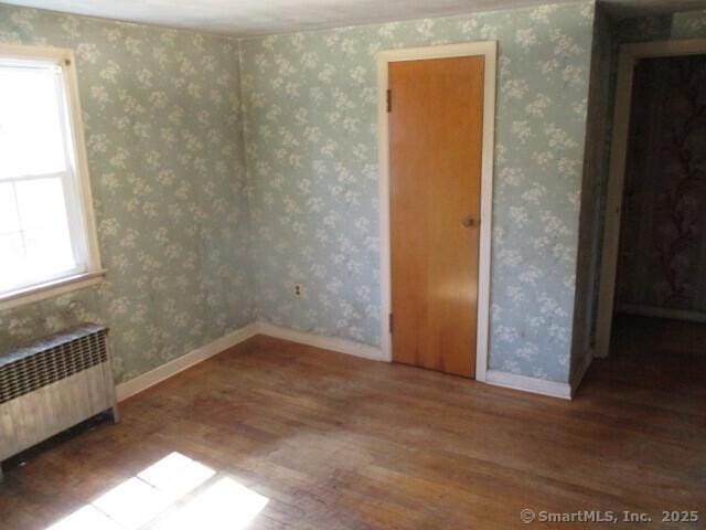spare room featuring wallpapered walls and radiator