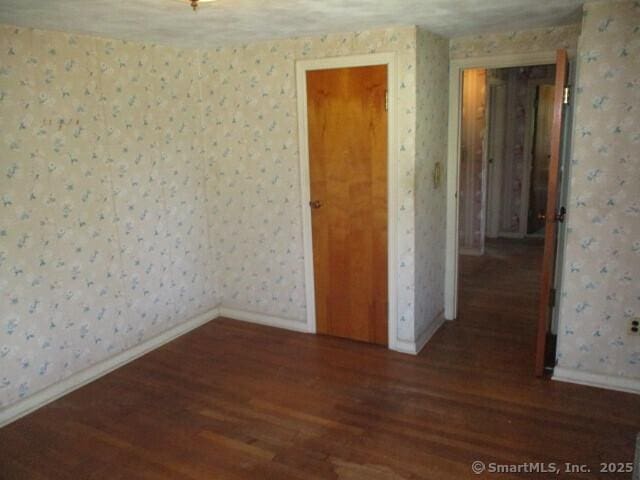 empty room with wallpapered walls and wood finished floors