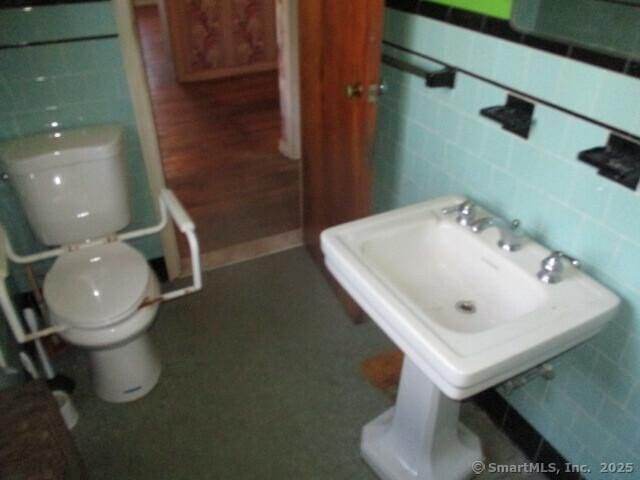 half bath with tile walls and toilet