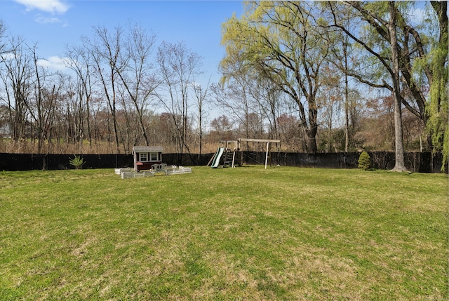 view of yard featuring an outdoor structure, a storage unit, a playground, and a fenced backyard