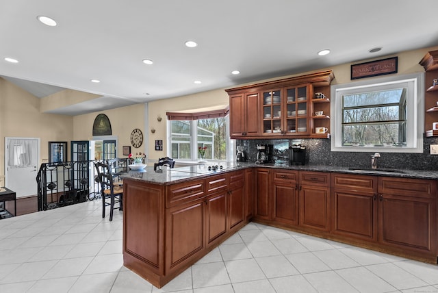 kitchen with open shelves, a peninsula, decorative backsplash, and a sink
