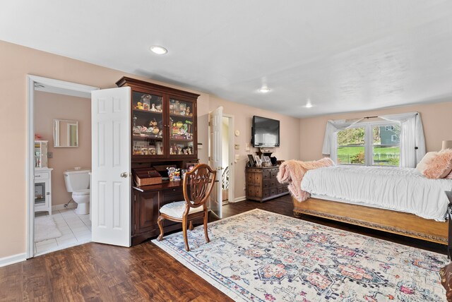 bedroom with ensuite bathroom, recessed lighting, dark wood finished floors, and baseboards