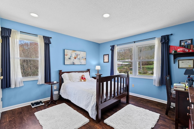 bedroom featuring baseboards, wood finished floors, and a textured ceiling