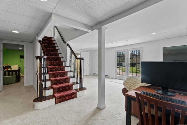 staircase with a baseboard heating unit, a paneled ceiling, and carpet