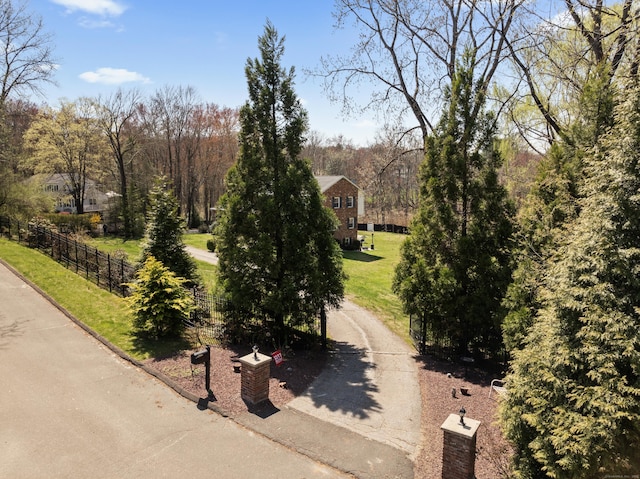 surrounding community with fence, driveway, and a lawn